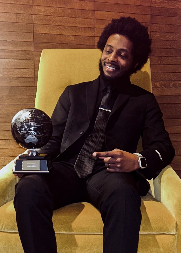 Capacity Expansion team member proudly holding a globe achievement award
